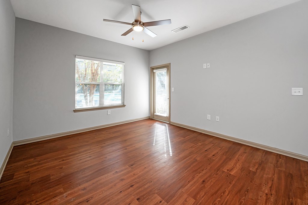 A room with a ceiling fan and wooden flooring.